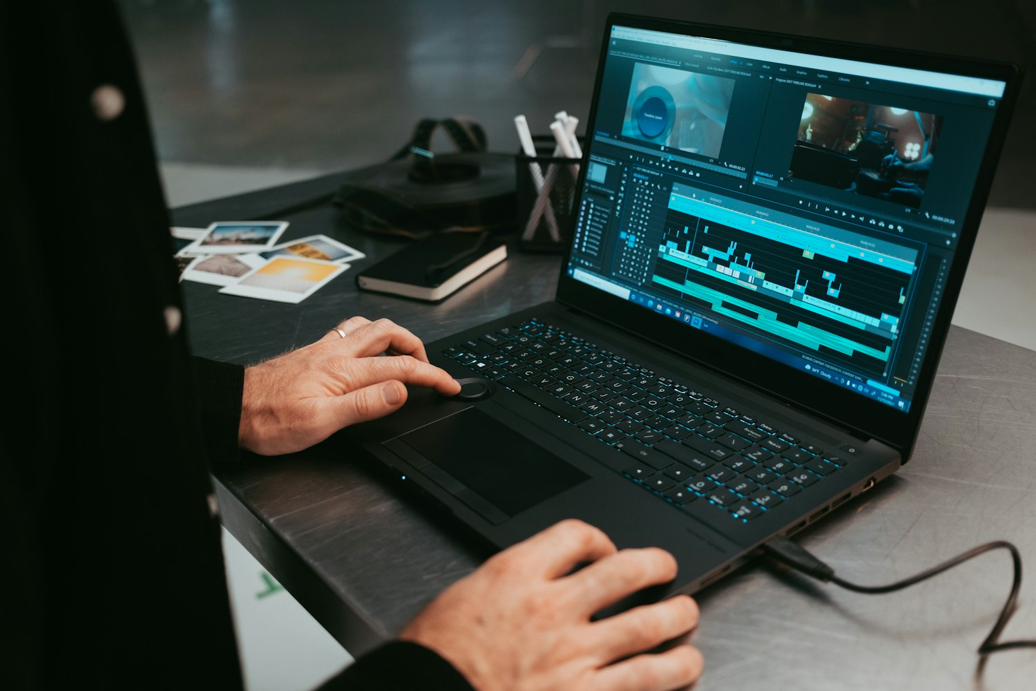 Người đeo kính biên tập video trên laptop và màn hình lớn